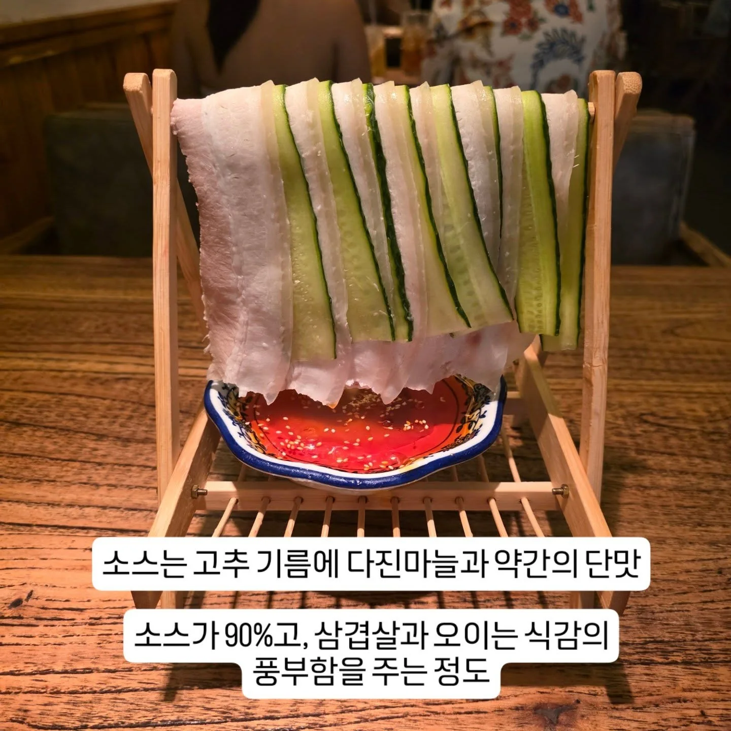 Thin slices of pork and cucumber hanging over chili oil